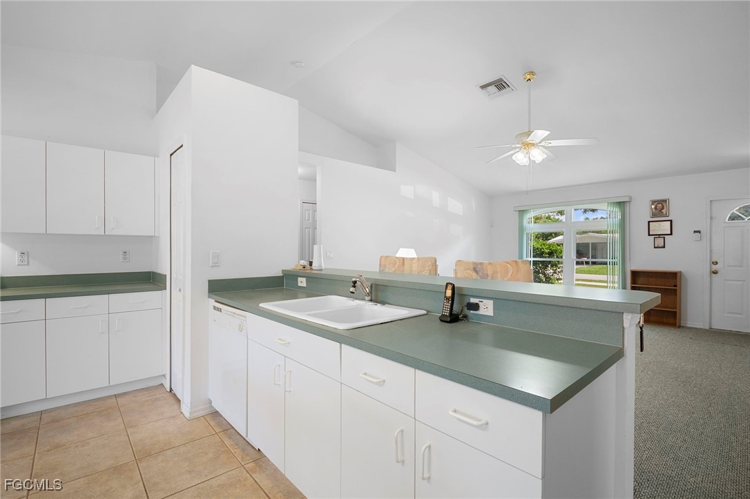 2932 Holly Road Fort Myers, FL 33901 - Photo 19 of 39 a kitchen with a sink dishwasher and white cabinets with wooden floor