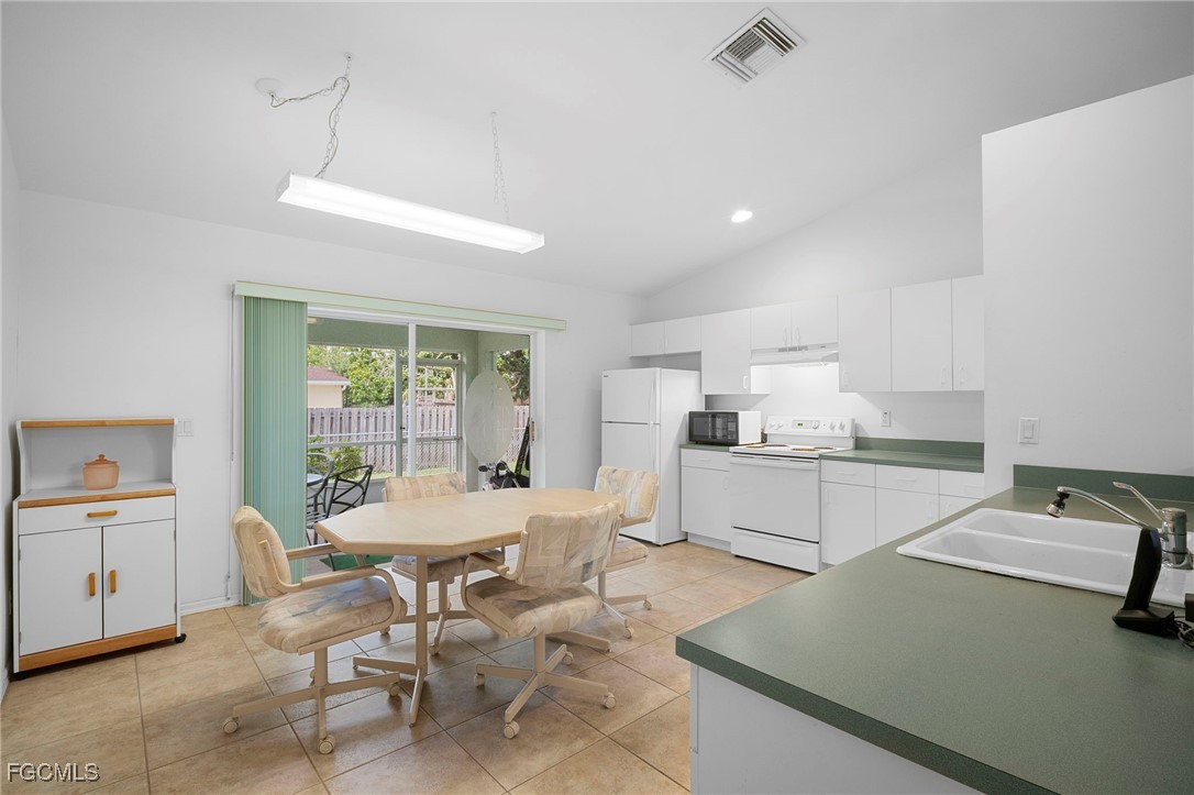 2932 Holly Road Fort Myers, FL 33901 - Photo 9 of 39 a kitchen with a dining table chairs and white cabinets