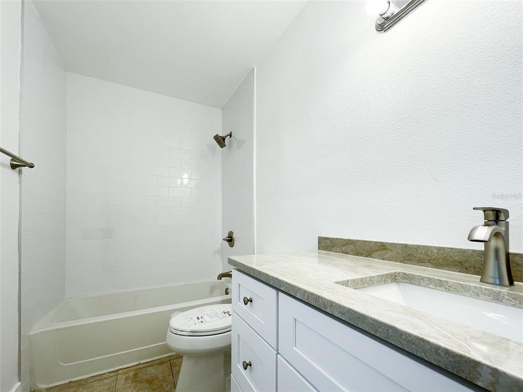 1400 Gandy Boulevard North, Unit 412 St. Petersburg, FL 33702 - Photo 15 of 44 a bathroom with a granite countertop sink a toilet and a shower