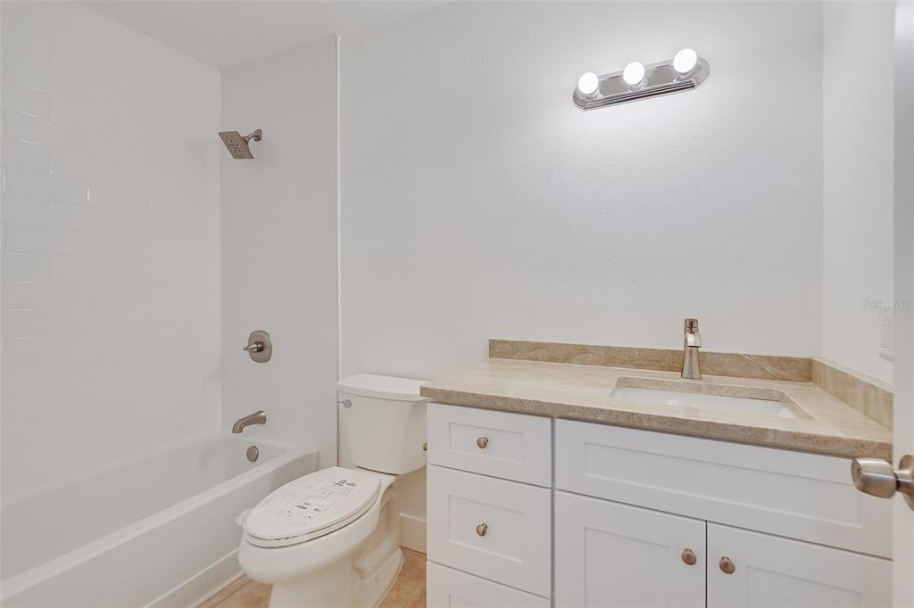 1400 Gandy Boulevard North, Unit 412 St. Petersburg, FL 33702 - Photo 19 of 44 a bathroom with a granite countertop toilet a sink and a bathtub