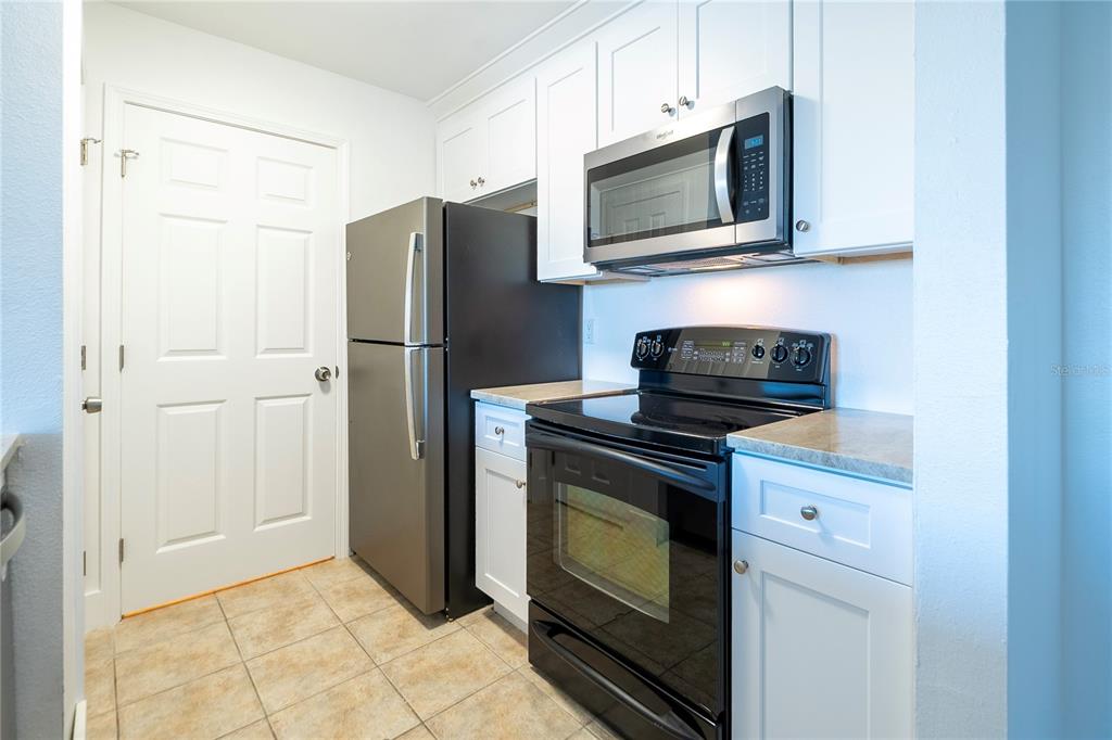 1400 Gandy Boulevard North, Unit 412 St. Petersburg, FL 33702 - Photo 9 of 44 a kitchen with stainless steel appliances white cabinets and a stove top oven