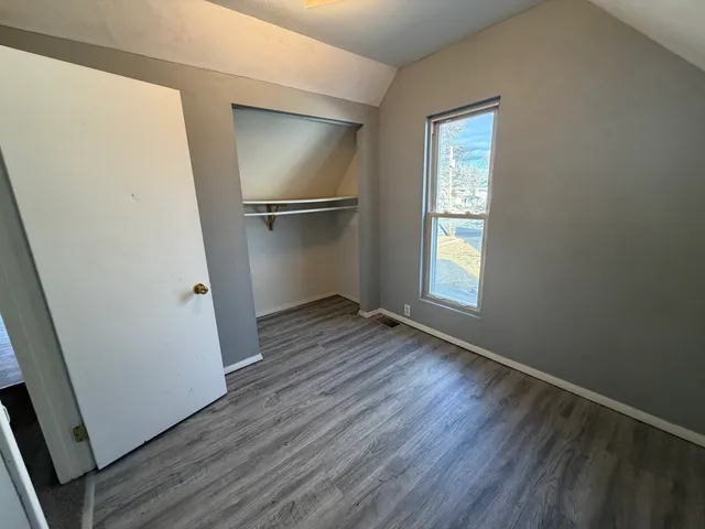 an empty room with wooden floor cabinet and windows