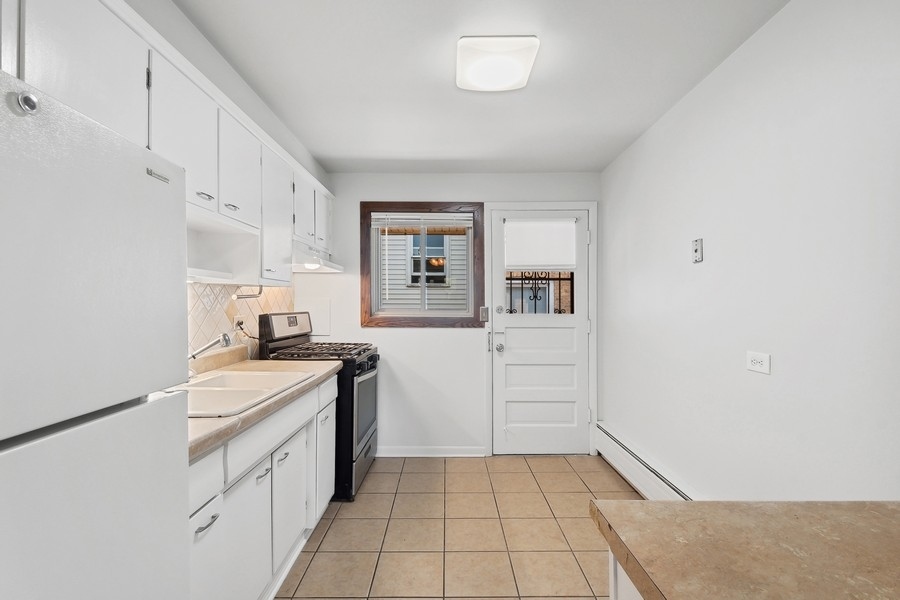 7019 North Ridge Boulevard, Unit 3B Chicago, IL 60645 - Photo 4 of 9 a kitchen with a sink a stove and cabinets