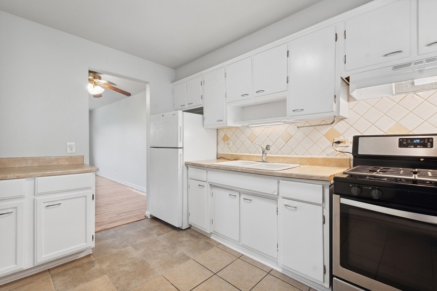 7019 North Ridge Boulevard, Unit 3B Chicago, IL 60645 - Photo 5 of 9 a kitchen with white cabinets and appliances