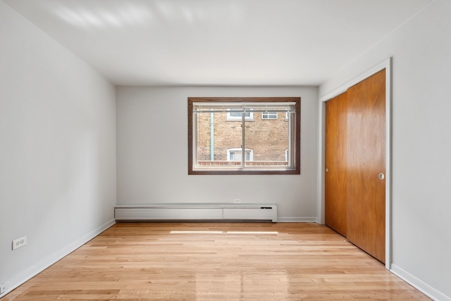 7019 North Ridge Boulevard, Unit 3B Chicago, IL 60645 - Photo 7 of 9 a view of an empty room with wooden floor and a window