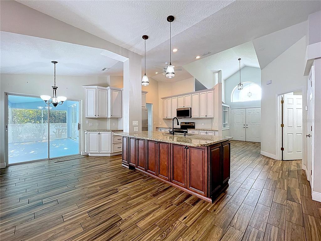 18812 Bascomb Lane Hudson, FL 34667 - Photo 26 of 57 a kitchen with stainless steel appliances kitchen island granite countertop wooden floors wooden cabinets and sink