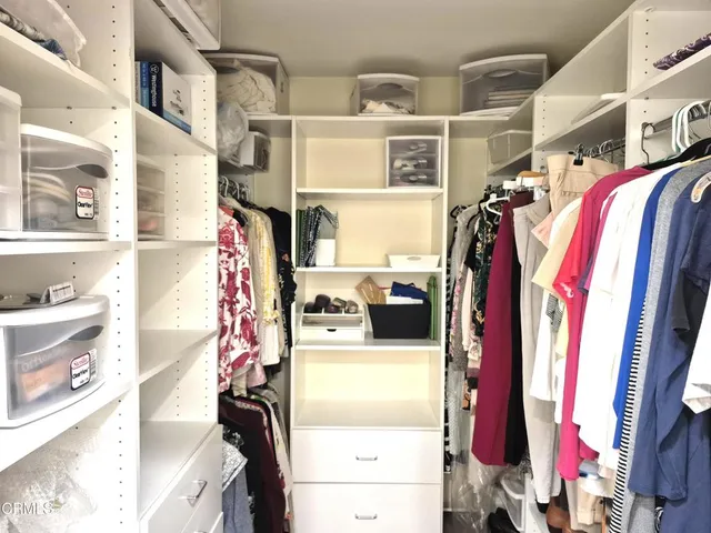 a view of walk in closet with clothes and shoes