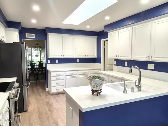 a kitchen with a sink kitchen island wooden cabinets and refrigerator
