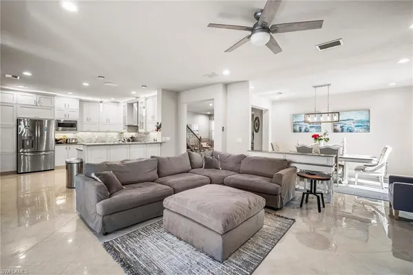 a living room kitchen with stainless steel appliances kitchen island a couches and kitchen view