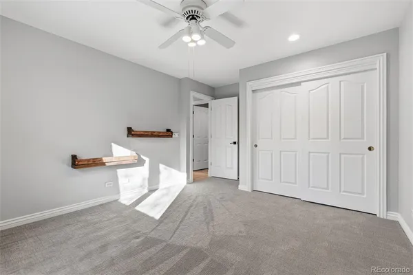 an empty room with chandelier fan and windows