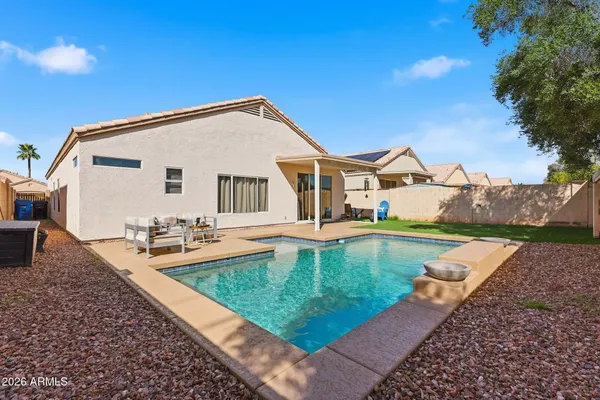 a view of a house with pool lawn chairs and a fire pit