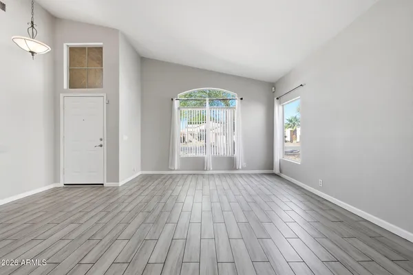 a view of an empty room with wooden floor and a window