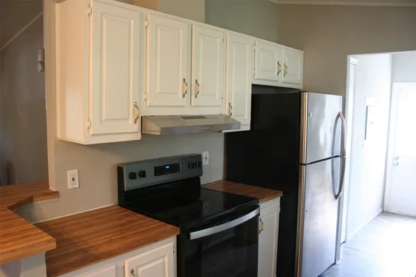 a kitchen with granite countertop white cabinets and refrigerator