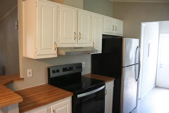 a kitchen with granite countertop white cabinets and refrigerator