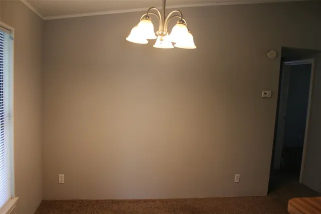 en empty room with window chandelier fan and windows