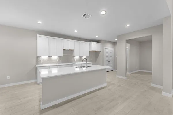 a large white kitchen with kitchen island a sink stainless steel appliances and cabinets