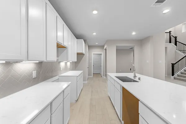 a large white kitchen with a sink and dishwasher a stove with wooden floor