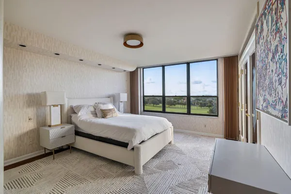 a bed sitting in a spacious bedroom next to a window