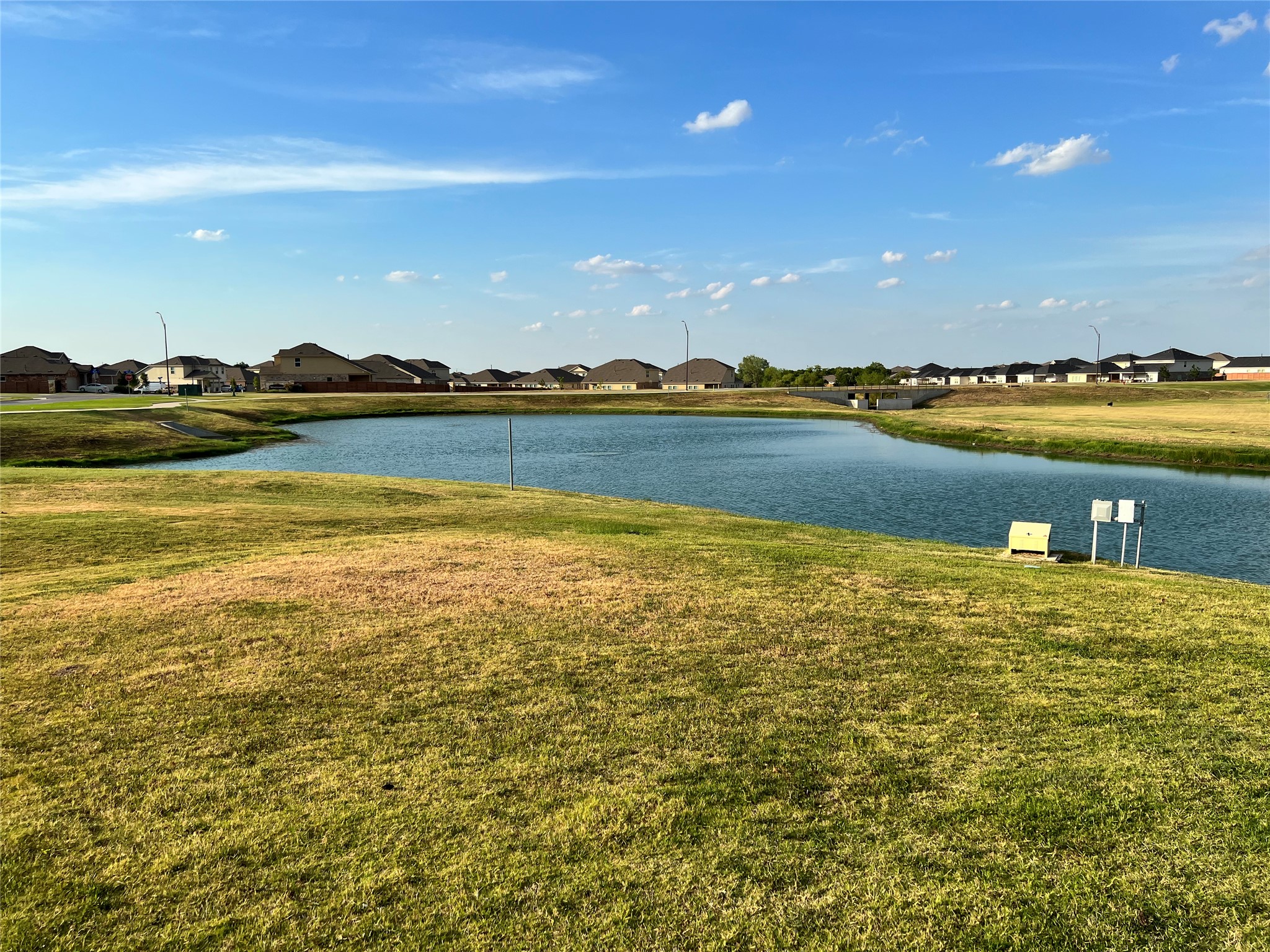 140 Pentro Path Georgetown, TX 78626 - Photo 24 of 37 Lush green lawns embrace this tranquil lake, providing a picturesque backdrop to a serene community.