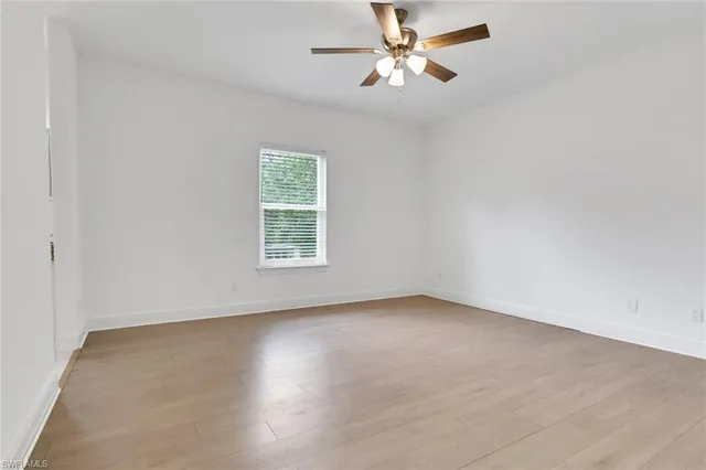 an empty room with wooden floor fan and windows