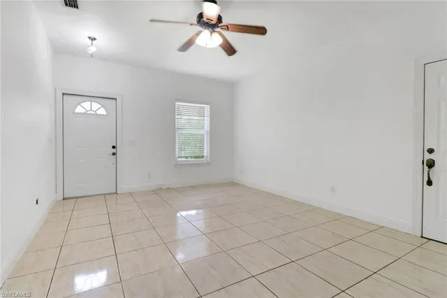 an empty room with windows and fan