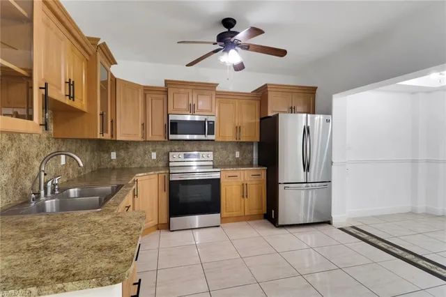 a kitchen with stainless steel appliances granite countertop a refrigerator a sink a stove a microwave and cabinets