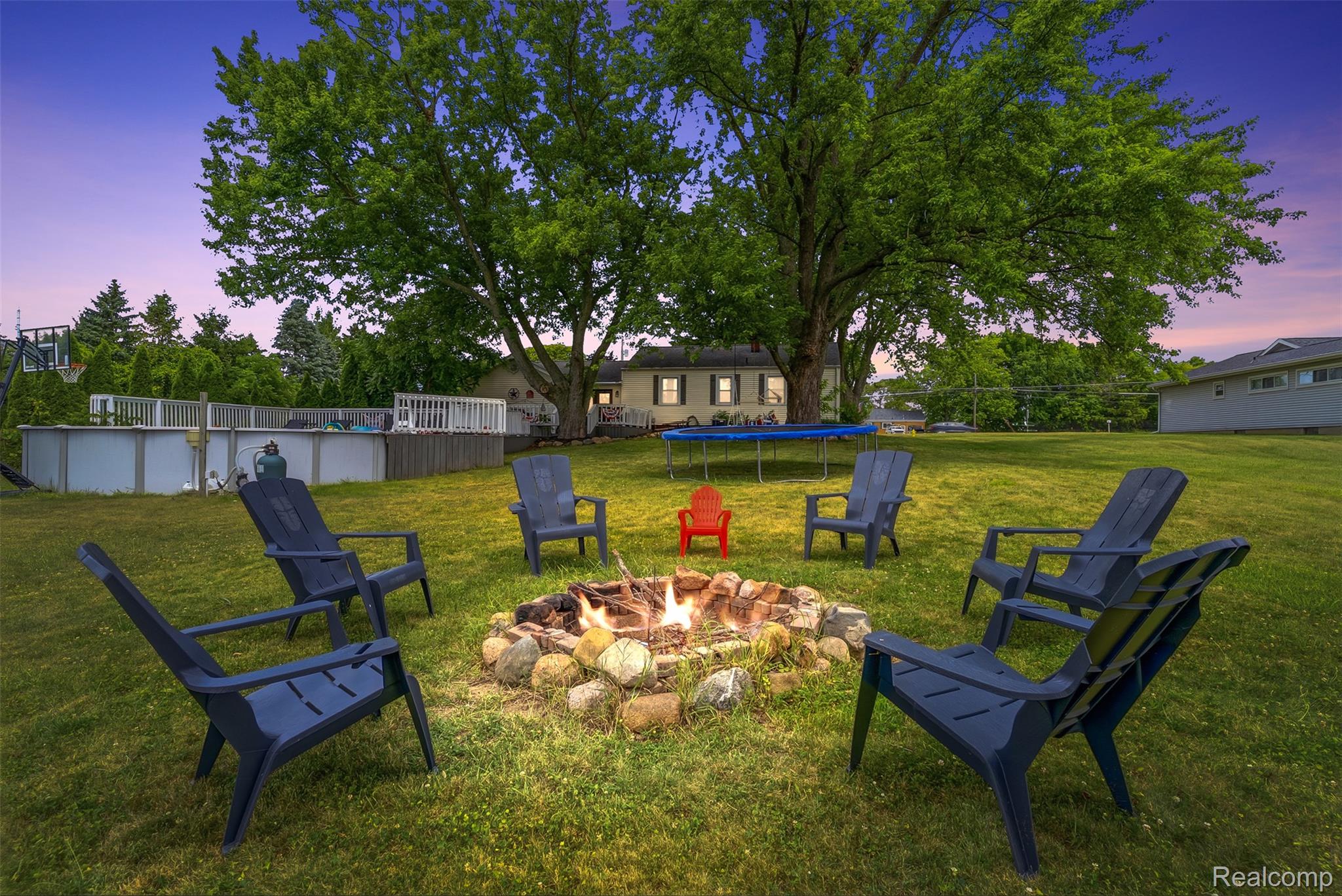 8403 Miller Road Swartz Creek, MI 48473 - Photo 30 of 37 Spacious backyard with a stone fire pit, mature trees, an above-ground pool with decking, and a large grassy area