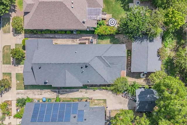 a view of a house with a small yard and large trees and plants