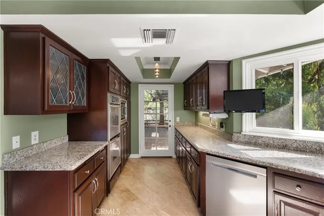 a kitchen with granite countertop kitchen island stainless steel appliances a sink stove and a refrigerator