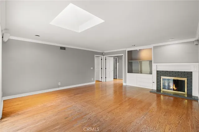 a view of an empty room with wooden floor fireplace and a window
