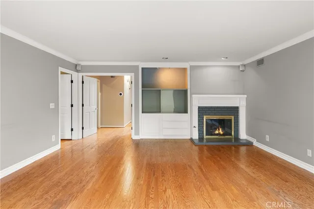 a view of empty room with wooden floor and fireplace