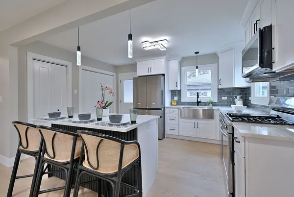 a kitchen with stainless steel appliances granite countertop a sink a stove a refrigerator and island with wooden floor