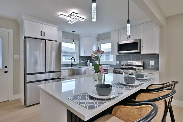 a kitchen with kitchen island granite countertop a sink a stove a refrigerator cabinets and dining table