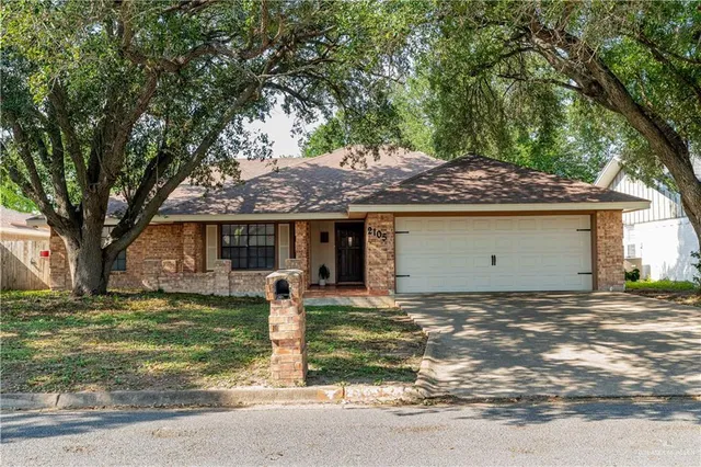 a front view of a house with a garden and tree