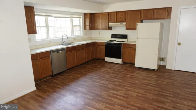 a kitchen with wooden floors and white stainless steel appliances