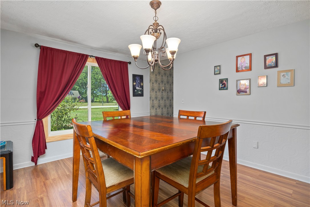 2565 Abbe Road North Sheffield Lake, OH 44054 - Photo 9 of 32 Dining area featuring wood-finish flooring, a contemporary chandelier, and a large window