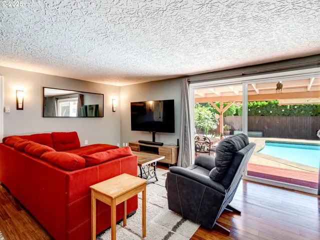 a living room with furniture a flat screen tv and a floor to ceiling window