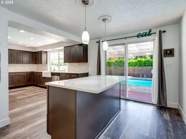 a kitchen with kitchen island granite countertop a stove and a wooden floor