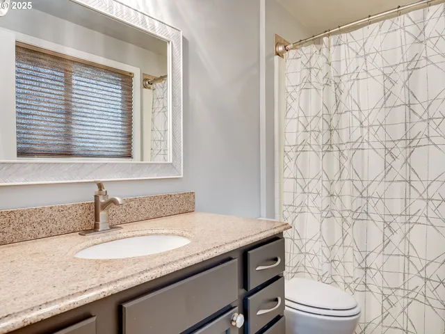 a bathroom with a granite countertop sink and a toilet