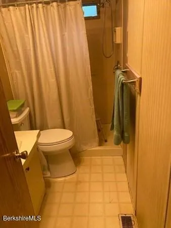 a bathroom with a granite countertop sink and a toilet