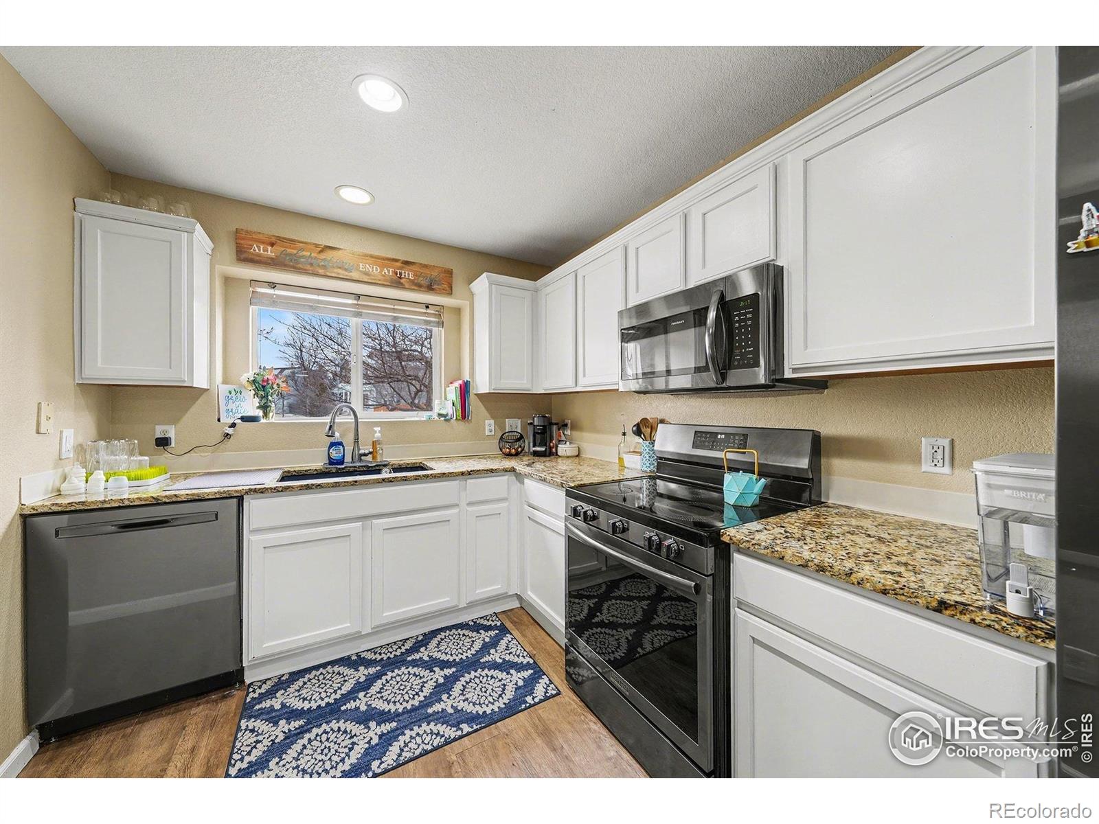 6815 Autumn Ridge Drive Fort Collins, CO 80525 - Photo 3 of 23 a kitchen with stainless steel appliances granite countertop a stove a sink dishwasher and a microwave oven with white cabinets