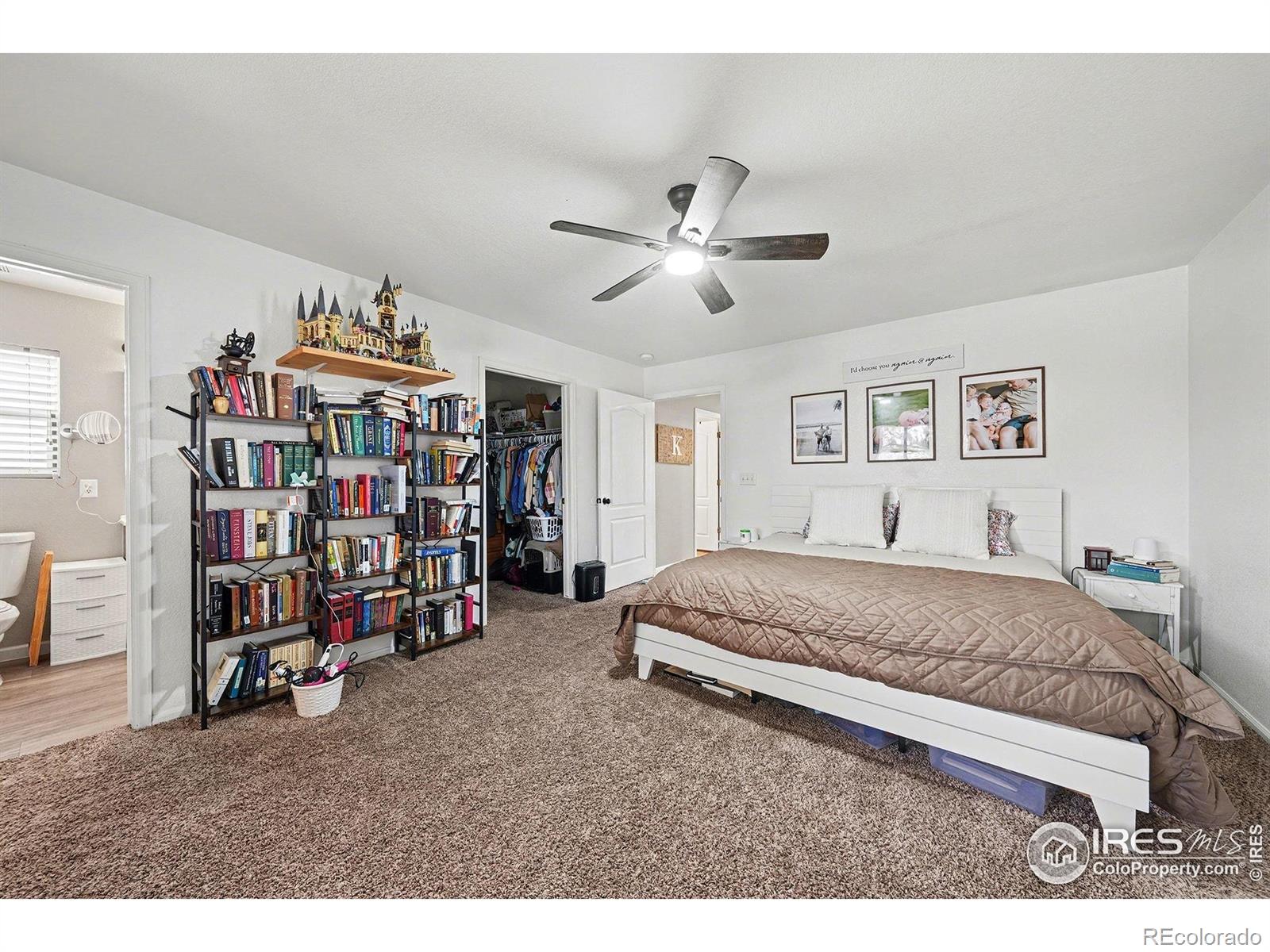 6815 Autumn Ridge Drive Fort Collins, CO 80525 - Photo 8 of 23 a spacious bedroom with a bed a book shelf and a chandelier
