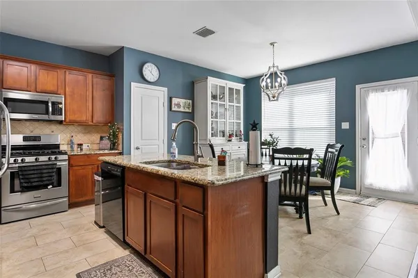 a kitchen with stainless steel appliances granite countertop a stove top oven a sink dishwasher a dining table and chairs with wooden floor