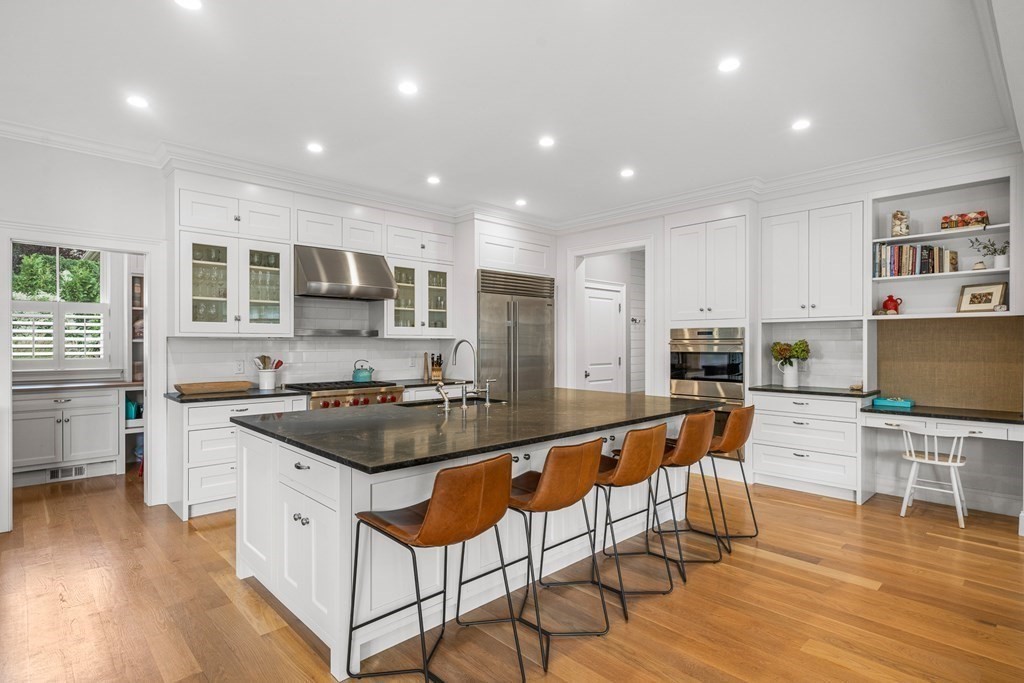 45 Bancroft Street Needham, MA 02492 - Photo 3 of 24 a kitchen with stainless steel appliances granite countertop a stove top oven a sink a dining table and chairs