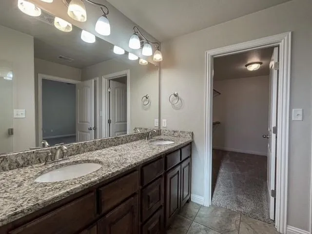 a bathroom with a granite countertop double vanity sink and a mirror