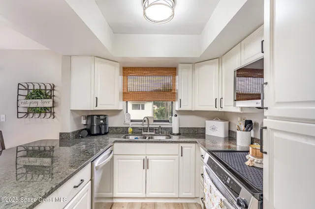 a kitchen with granite countertop a sink a stove and cabinets