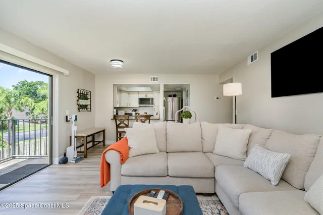 a living room with furniture a flat screen tv and a large window