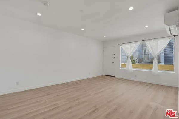 an empty room with wooden floor and window
