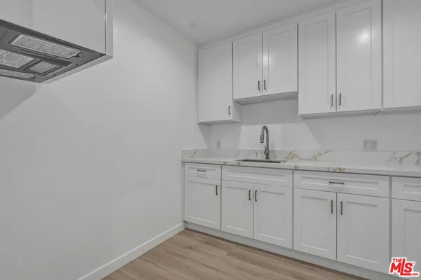 a kitchen with white cabinets and sink