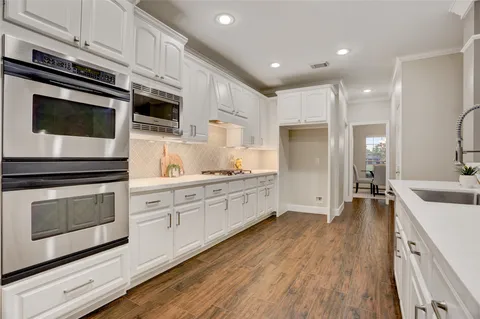 a large kitchen with stainless steel appliances kitchen island granite countertop a stove a sink and a microwave